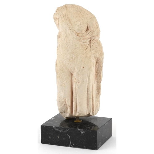 412 - Hellenistic style carving of a scantily dressed female wearing a robe raised on a rectangular black ... 