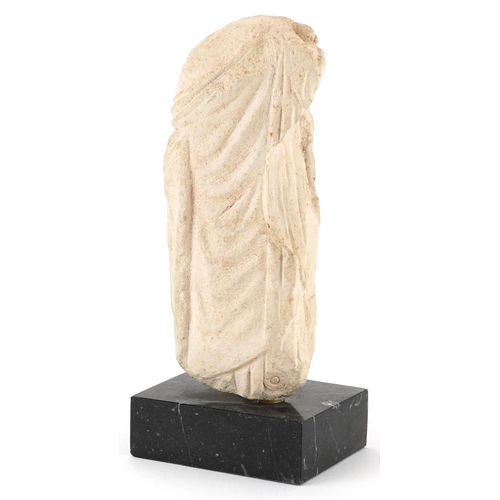 412 - Hellenistic style carving of a scantily dressed female wearing a robe raised on a rectangular black ... 