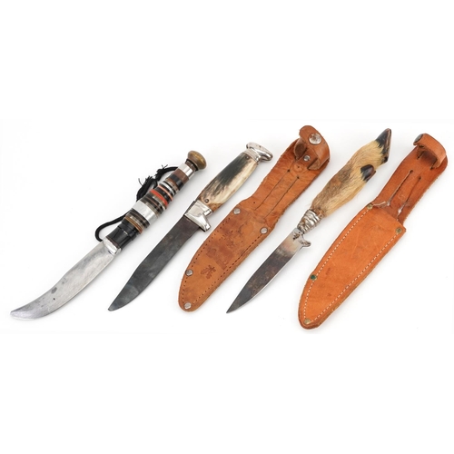 672 - Three vintage hunting knives including a taxidermy example with deer's foot, two with leather sheath... 