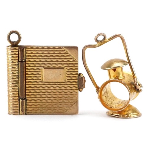 2595 - Two 9ct gold charms in the form of a book and railway lantern with swing handle, the largest 1.9cm h... 