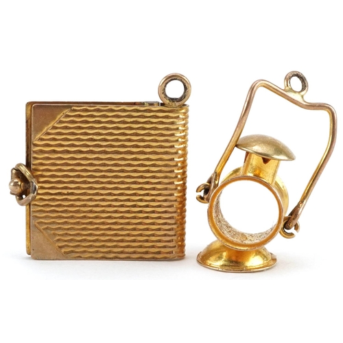 2595 - Two 9ct gold charms in the form of a book and railway lantern with swing handle, the largest 1.9cm h... 