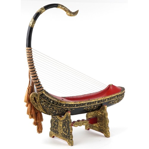  Large Burmese black and red lacquered Saung-gauk harp on stand, each gilt decorated in low relief wi... 