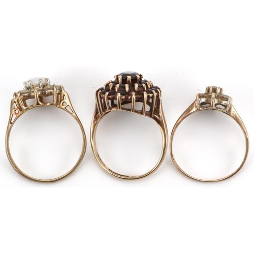 2554 - Three 9ct gold rings comprising Bohemian garnet three tier cluster, cabochon opal and cubic zirconia... 