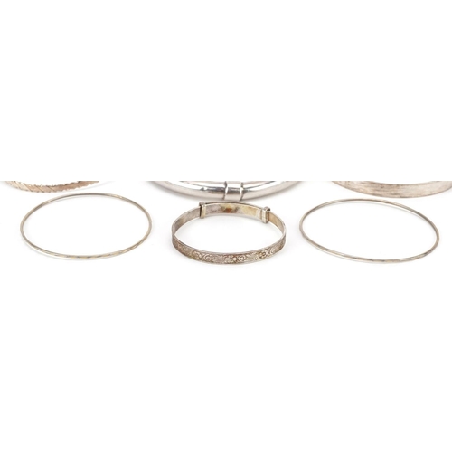 2704 - Six silver and white metal bangles including a christening bangle, the largest 8cm in diameter, tota... 