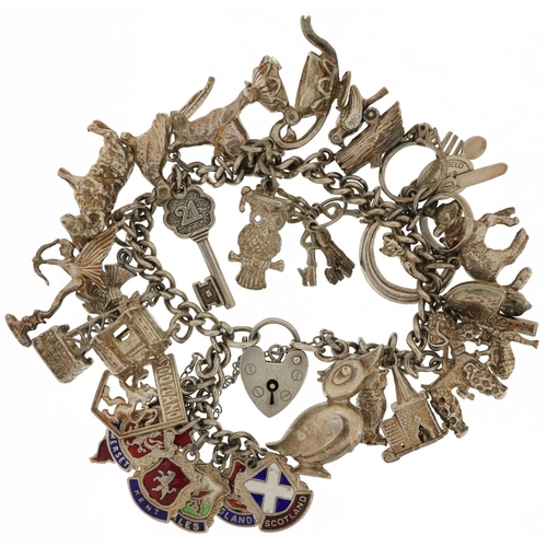 2107 - Heavy silver charm bracelet with a collection of mostly silver charms including Cupid, enamelled sou... 