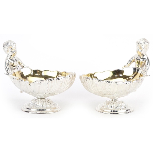 1506 - Pair of silver plated open salts in the form of Putti holding a seashell, 12cm in length