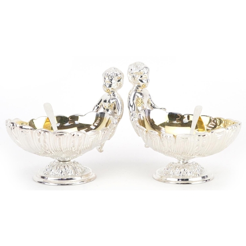 1506 - Pair of silver plated open salts in the form of Putti holding a seashell, 12cm in length