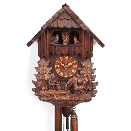 442 - German Black Forest wall clock carved with a farrier beside horse and foal, 36cm high