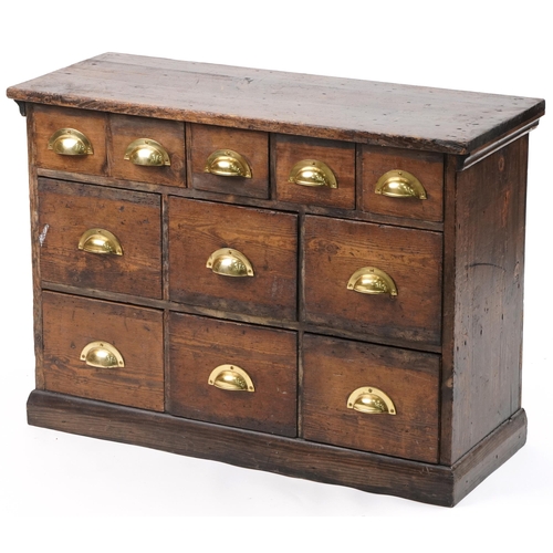 1012 - Stained pine haberdashery chest fitted with an arrangement of eleven drawers having brass handles, 6... 