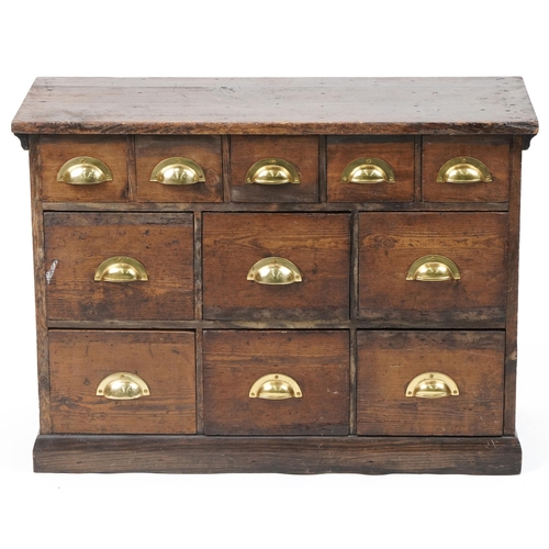 1012 - Stained pine haberdashery chest fitted with an arrangement of eleven drawers having brass handles, 6... 