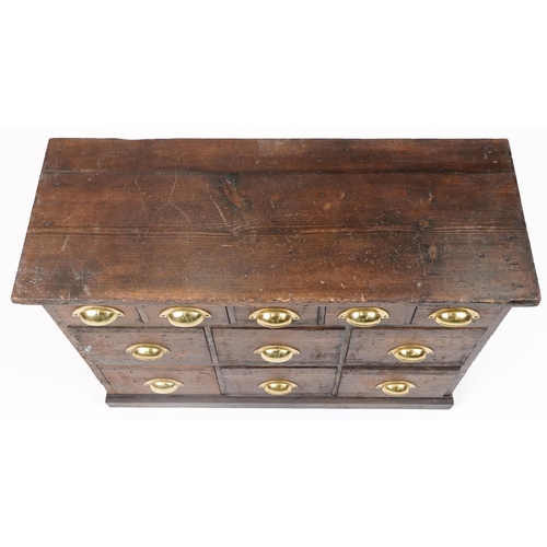 1012 - Stained pine haberdashery chest fitted with an arrangement of eleven drawers having brass handles, 6... 