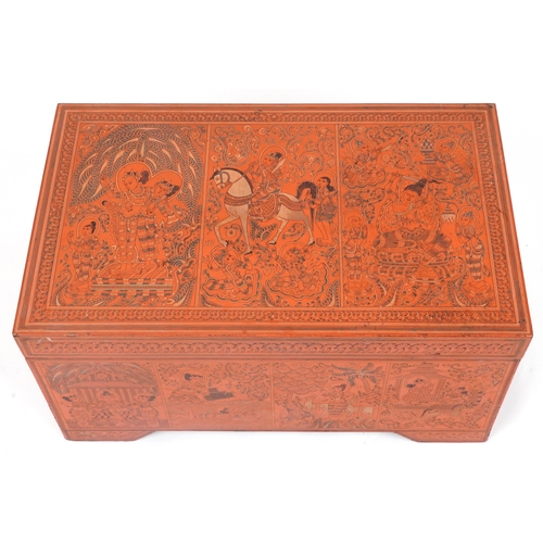 1065 - Burmese red lacquered trunk with hinged lid profusely hand painted with panels of deities in landsca... 