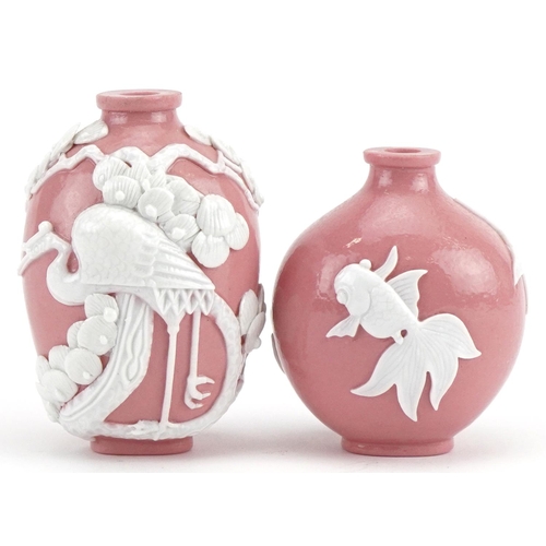 554 - Two Chinese porcelain pink ground snuff bottles decorated in relief with fish and a crane, the large... 