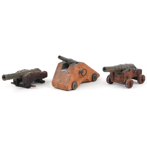 34 - Three 19th/20th century military interest patinated bronze  and hardwood table cannons, the largest ... 