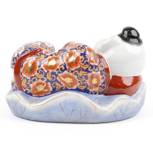 1339 - Chinese porcelain figure of a sleeping boy hand painted in the Imari palette, 24cm wide