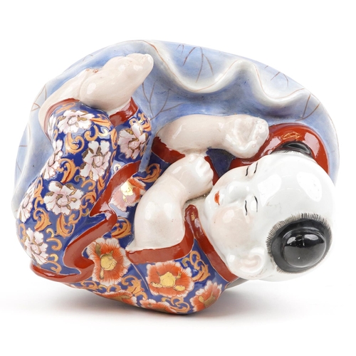 1339 - Chinese porcelain figure of a sleeping boy hand painted in the Imari palette, 24cm wide