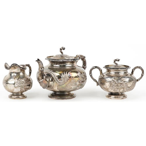 Chinese export silver three piece tea service having simulated bamboo handles embossed with dragons, possibly by Hung Chong, the teapot 22cm in length, total 1080.0g