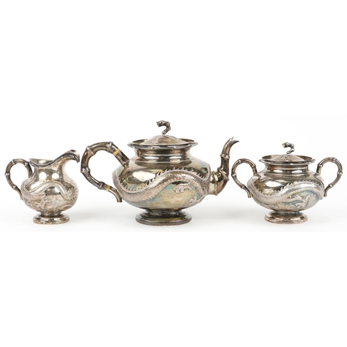 15 - Chinese export silver three piece tea service having simulated bamboo handles embossed with dragons,... 