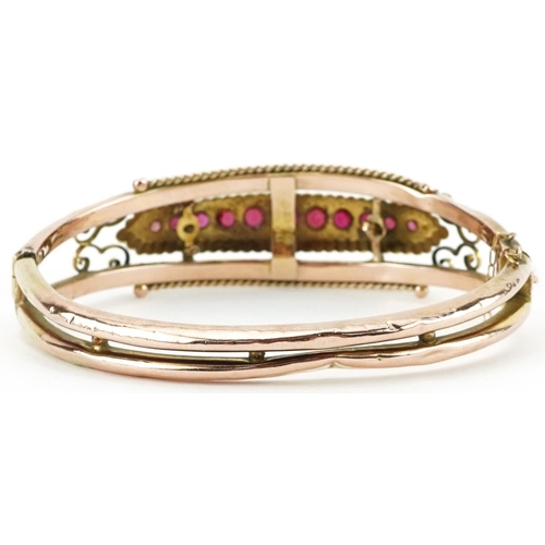 2247 - Edwardian 9ct rose gold hinged bangle set with eleven graduated red stones and seed pearls, Chester ... 