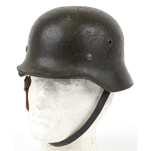 German military interest tin helmet with leather liner and chin strap, indistinct impressed marks to the helmet