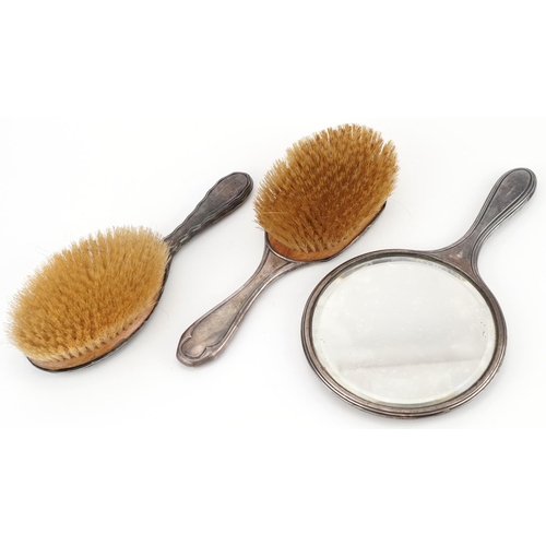 268 - Two Edwardian silver backed clothes brushes and a hand mirror, the largest 27cm in length