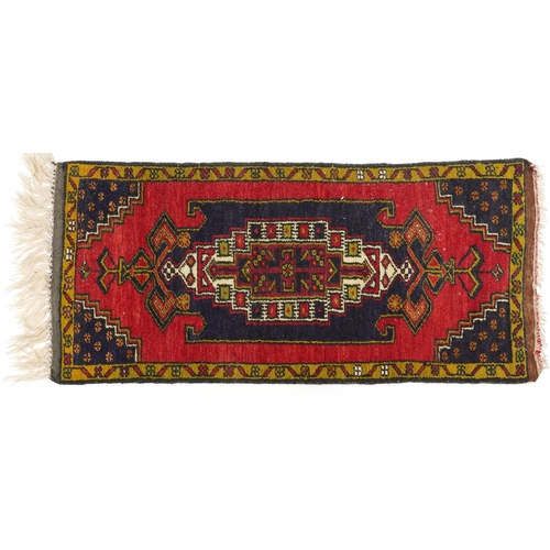 1219 - Rectangular Persian red and blue ground rug having an allover repeat floral design, 120cm x 53.5cm