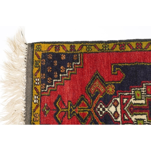 1219 - Rectangular Persian red and blue ground rug having an allover repeat floral design, 120cm x 53.5cm