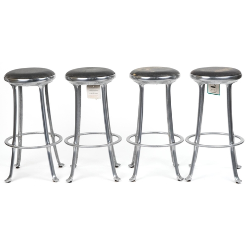 1173 - Set of four industrial chromed bar stools with black upholstered cushioned seats, 69cm high