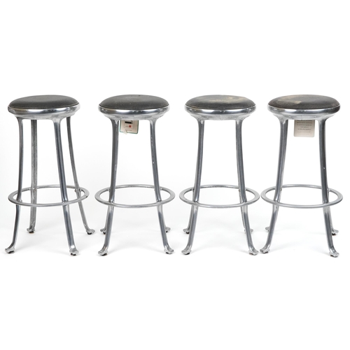 1173 - Set of four industrial chromed bar stools with black upholstered cushioned seats, 69cm high