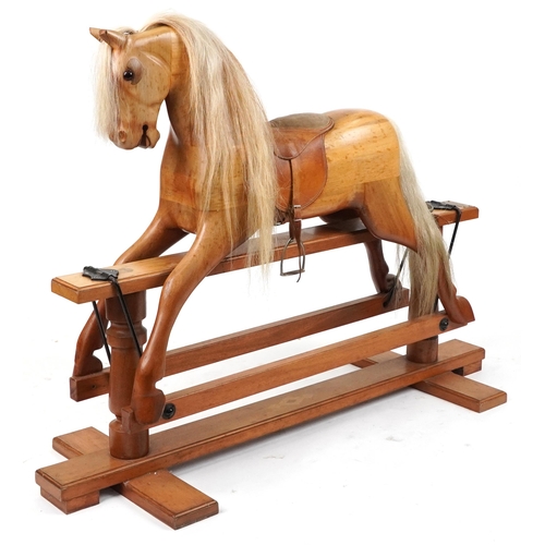 Large carved hardwood rocking horse with leather saddle on hardwood stand having brass plaque engraved G N Mayes King's Norton Lodge near Billesdon, Leicester, 140cm in length
