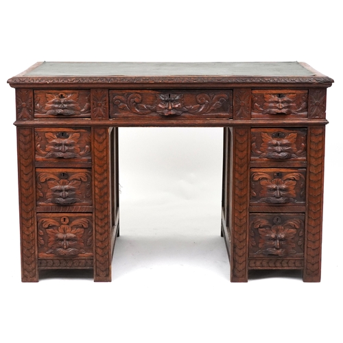 1015 - Victorian oak twin pedestal desk carved with a green man masks, fitted with an arrangement of nine d... 