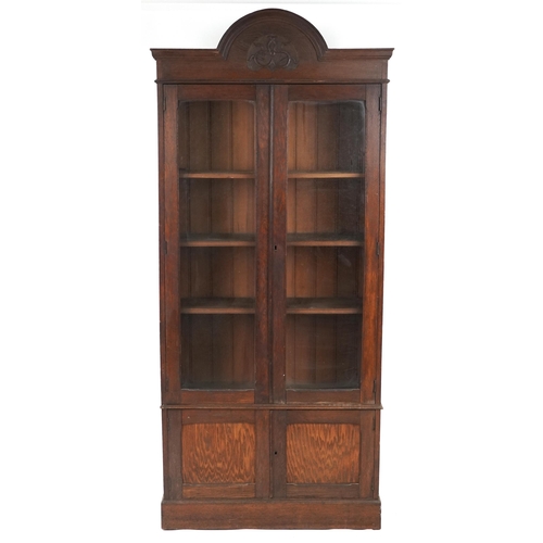 1072 - Art Nouveau oak glazed bookcase fitted with three adjustable shelves above a cupboard base, 228cm H ... 