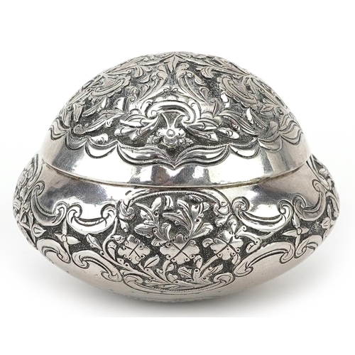 299 - Tibetan unmarked silver bun shaped box with hinged lid profusely embossed with flowers and foliage, ... 