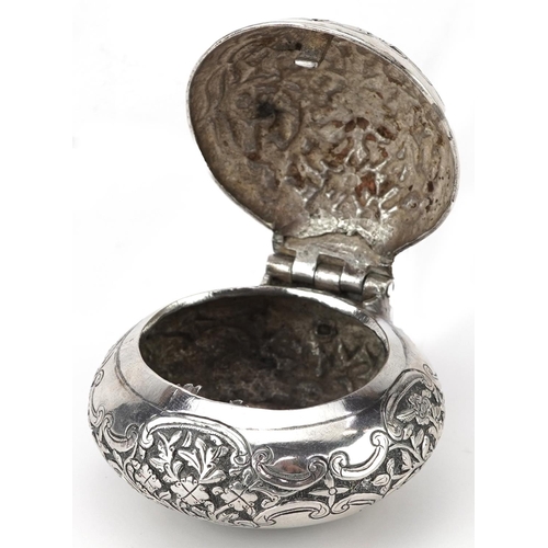 299 - Tibetan unmarked silver bun shaped box with hinged lid profusely embossed with flowers and foliage, ... 