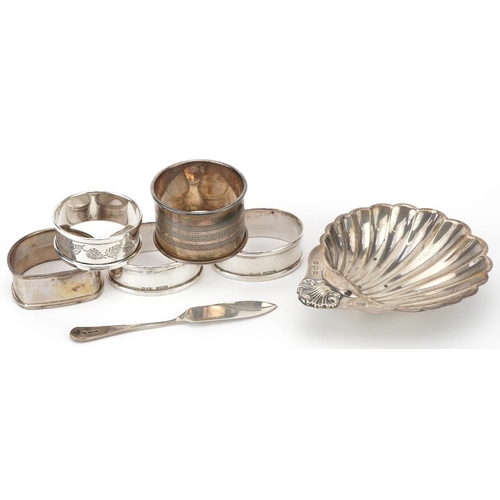 176 - Edwardian and later silver objects comprising five napkin rings, butter knife and shell shaped dish ... 