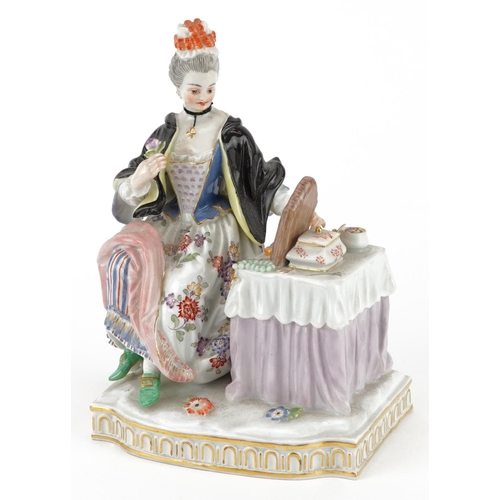 125 - Meissen, German porcelain figure of a female sitting beside a dressing table with mirror holding a f... 