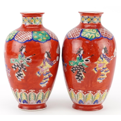 623 - Pair of Japanese iron red ground porcelain vases hand painted with a continuous band of Geishas danc... 