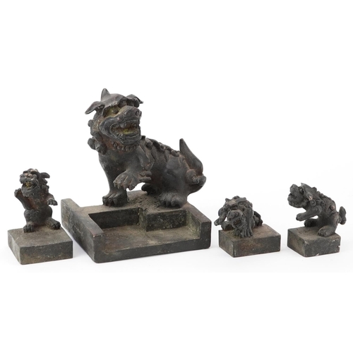 626 - Set of four Chinese patinated bronze interlocking desk seals in the form of qilins, 12cm high