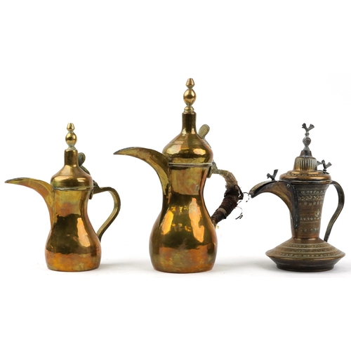 293 - Three Omani brass dallah coffee pots including an example with bird knops, the two others with impre... 