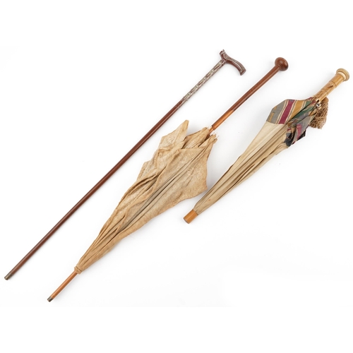 615 - Two early 20th century parasols and a Middle Eastern hardwood walking stick with foliate metal inlay... 