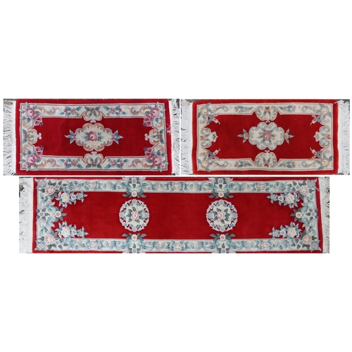 1223 - Three Chinese red ground floral rugs including a runner, the largest 255cm x 70cm