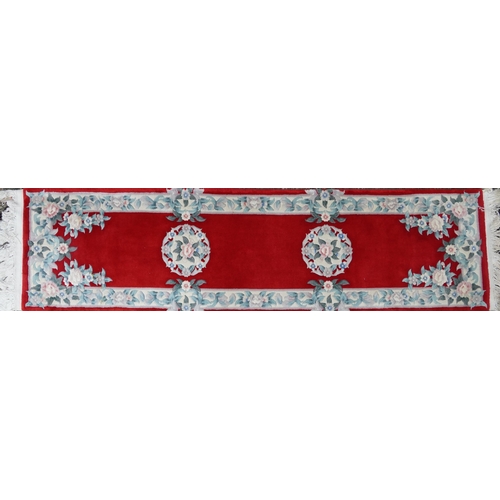 1223 - Three Chinese red ground floral rugs including a runner, the largest 255cm x 70cm