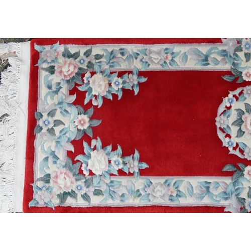 1223 - Three Chinese red ground floral rugs including a runner, the largest 255cm x 70cm