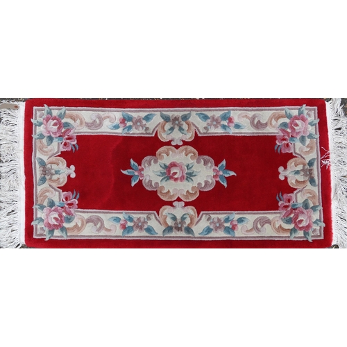 1223 - Three Chinese red ground floral rugs including a runner, the largest 255cm x 70cm