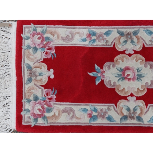 1223 - Three Chinese red ground floral rugs including a runner, the largest 255cm x 70cm