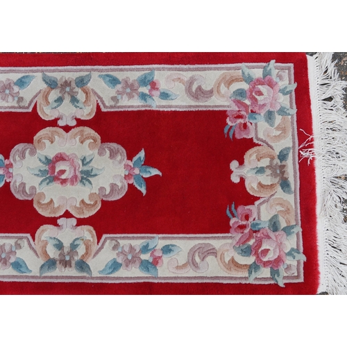 1223 - Three Chinese red ground floral rugs including a runner, the largest 255cm x 70cm