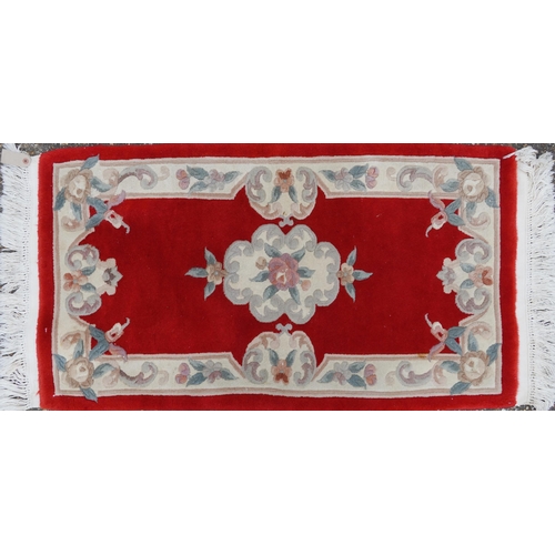 1223 - Three Chinese red ground floral rugs including a runner, the largest 255cm x 70cm