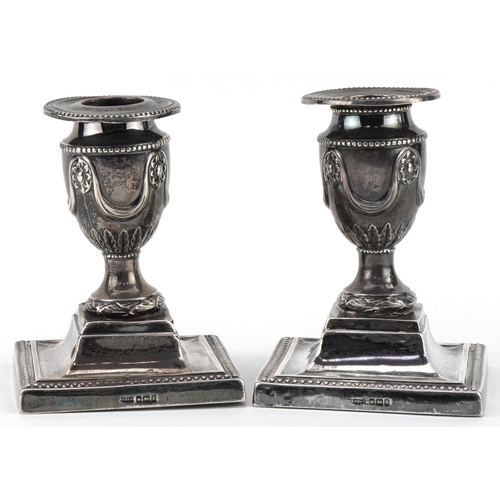 511 - James Dixon & Sons, pair of Edwardian silver campana urn dwarf candlesticks embossed with flowers an... 