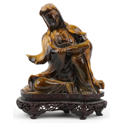 122 - Chinese tiger's eye carving of Guanyin raised on hardwood stand carved with foliage, 16cm high