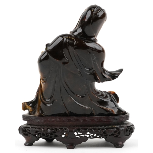 122 - Chinese tiger's eye carving of Guanyin raised on hardwood stand carved with foliage, 16cm high